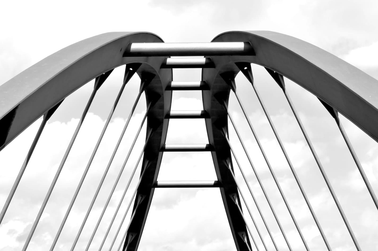 Close-up view of a modern steel arch bridge, showing curved structural supports
