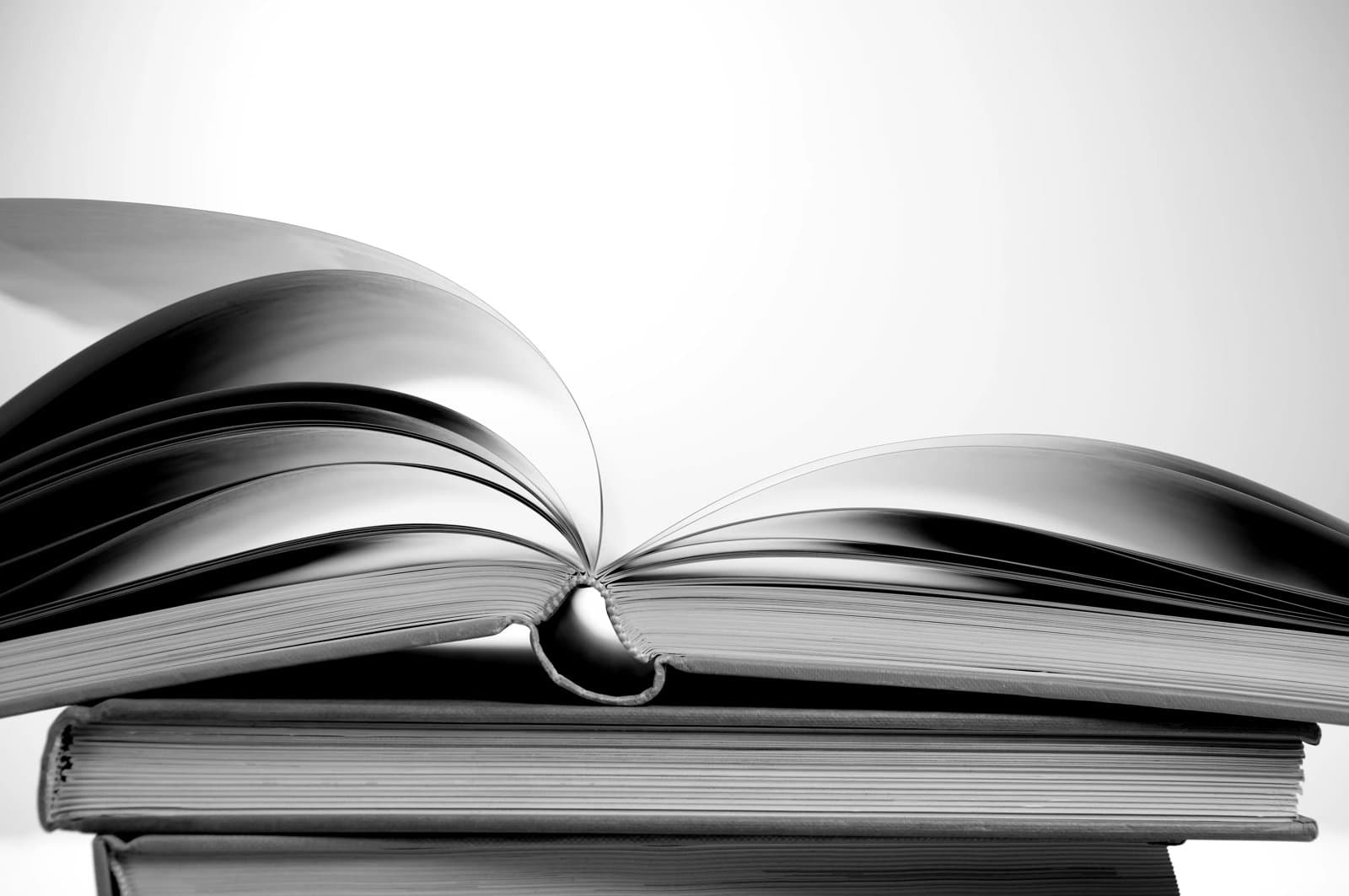A stack of books with the top book lying open half way through.