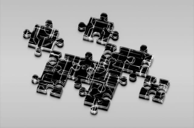 Transparent jigsaw puzzle pieces overlaid with circuit‑board patterns, arranged loosely on a light surface.
