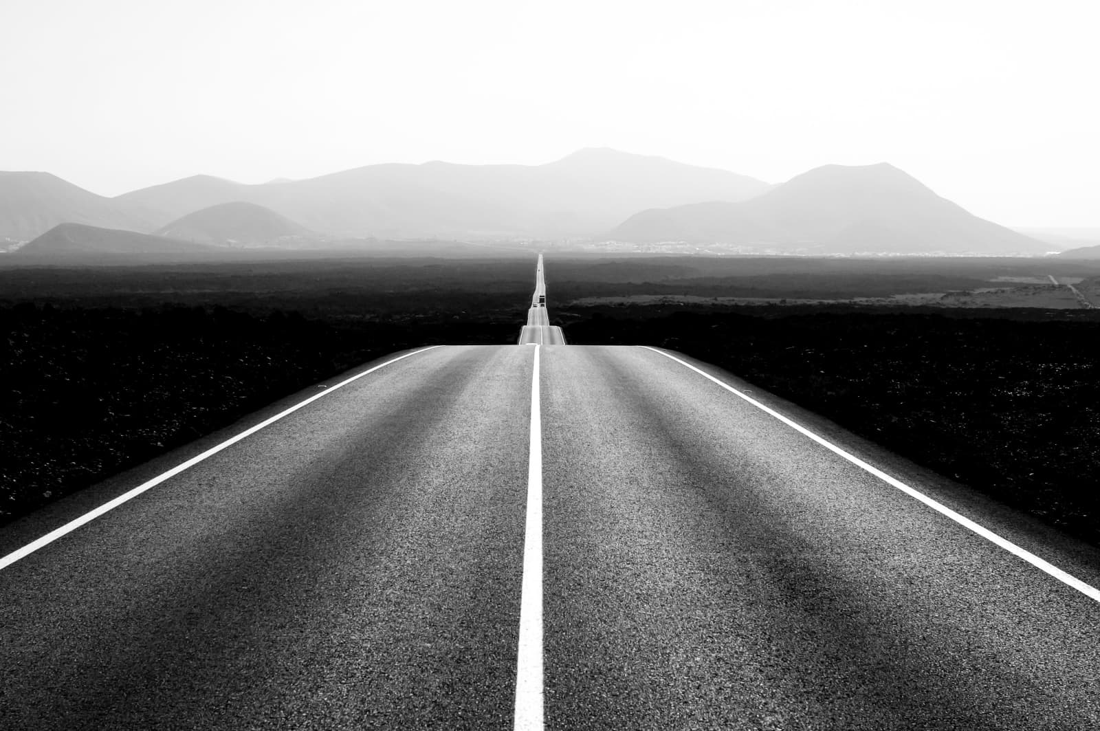 Road leading towards mountains in the middle of a desert