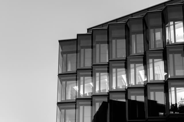 A modern glass building façade with repeating angular window panels.
