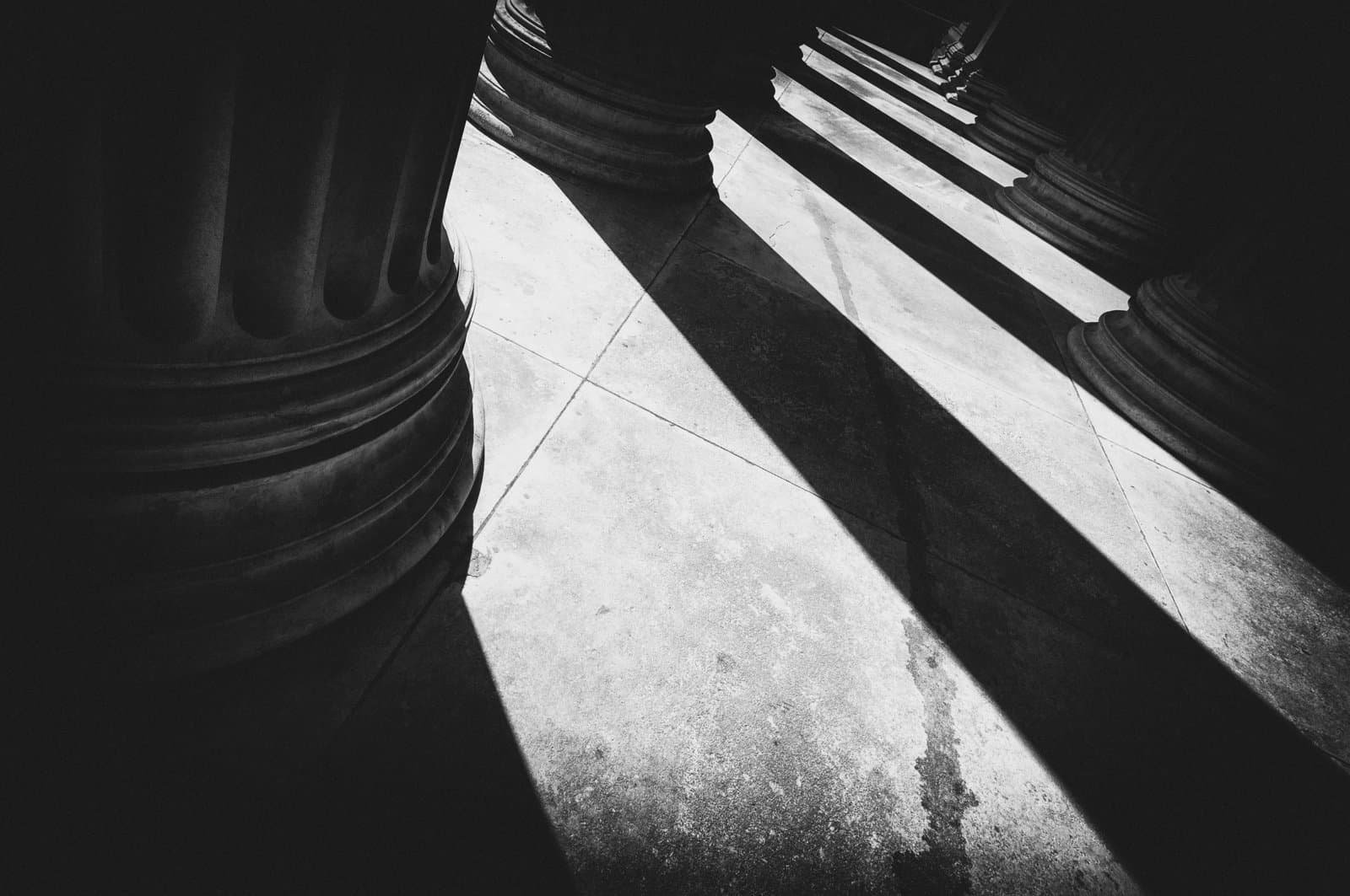 Stone columns casting long shadows across a floor